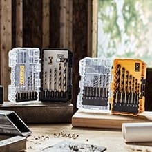 Two boxes filled with drill bits standing on wood and stone