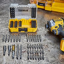 Individual screwdriver bits lie spread out in front of a storage box